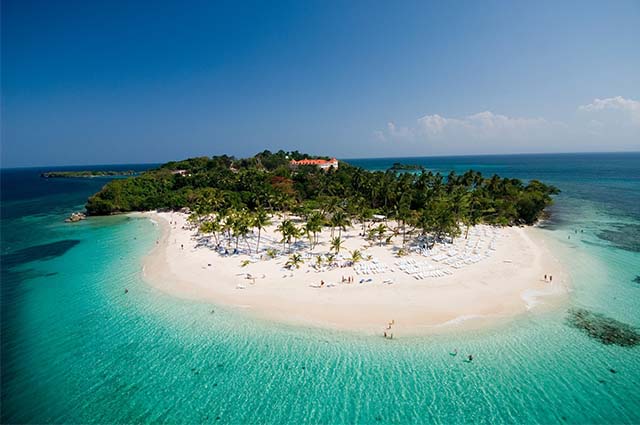 Photo of a sandy beach with turquoise water in the Dominican Republic with green rainforest