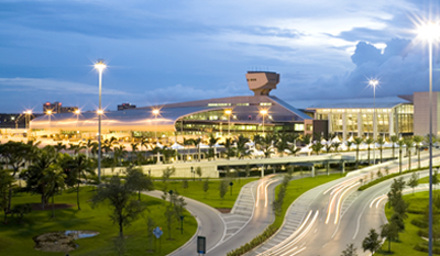 Miami International Airport exterior shot, showing the modern main terminal building lit up at dusk 