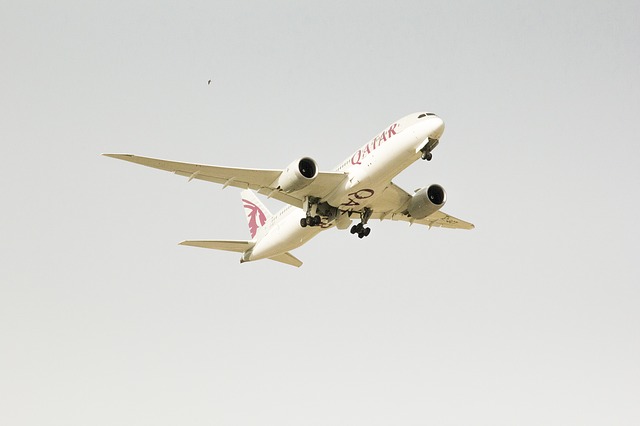 Qatar Airways plane flying across grey sky