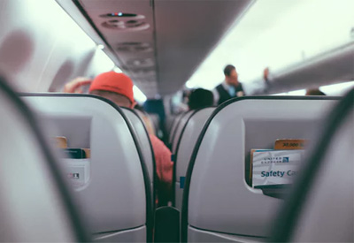 view though the gap between airplane seats, showing flight attendant talking to passengers