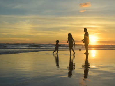 Photo of a family playing on a beach at sunset