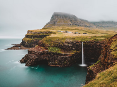 Scenic shot of the Faroe Islands shows rugged cliffs, mist, and a waterfall