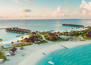 A shot looking down at a beach resort in the Maldives, with sandy beach and calm water